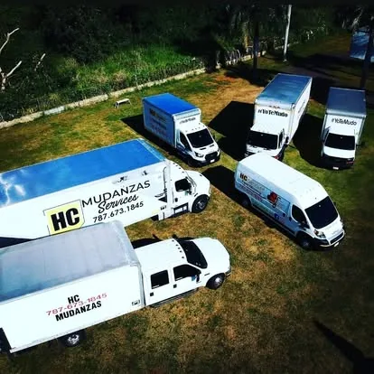 Vista aérea de la flota de HC Services: seis camiones y vans de mudanza rotulados, estacionados juntos